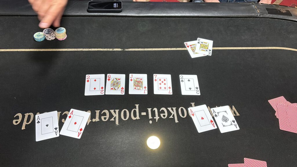 Könige verlieren gegen zwei Spieler mit Assen mit den Community-Cards Dame, Bube, 7, 2 und 2.